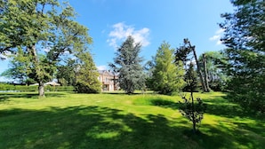 A well-maintained lawn with a large building in the background. - Les Tuileries du Buisson (Verneuil d'Avre et d'Iton)