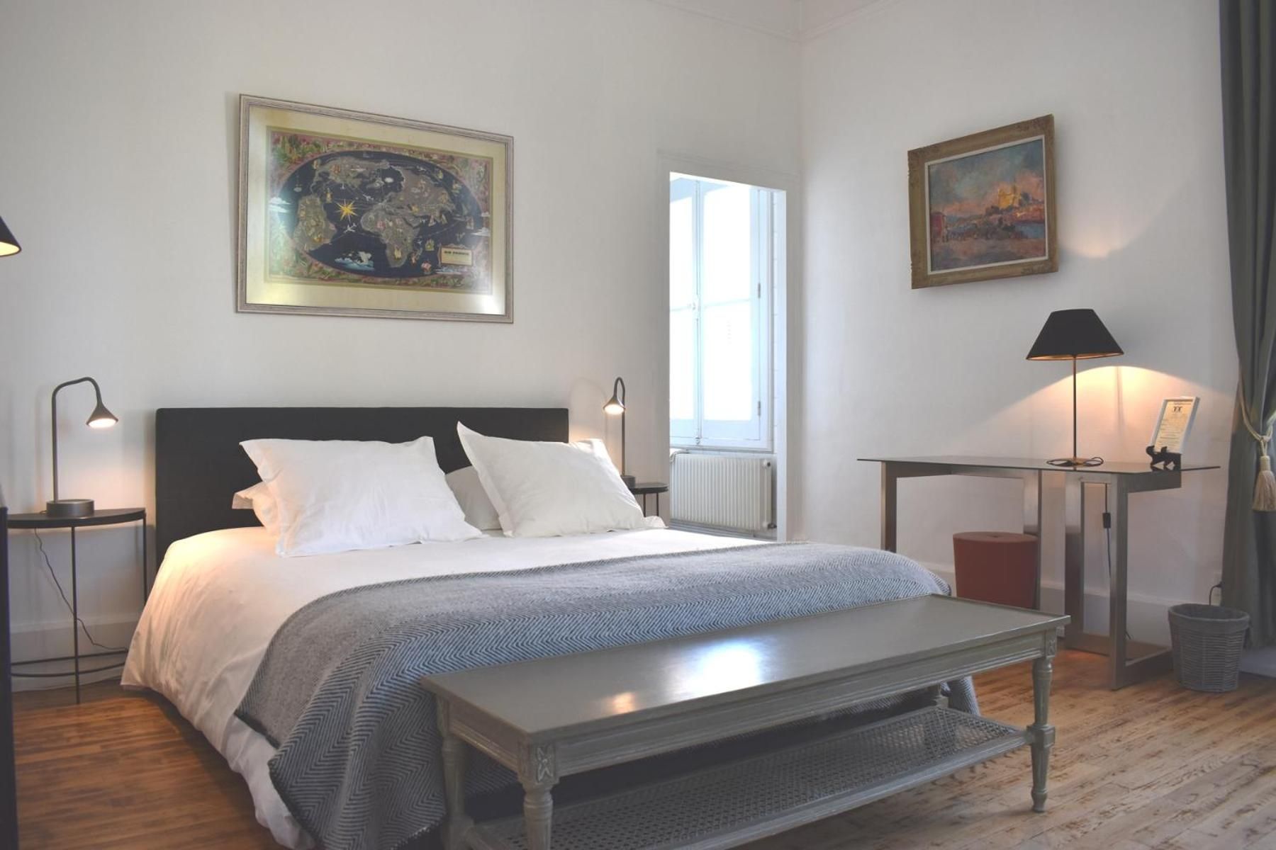 A bedroom with a bed, bedside tables, a desk, and a window.