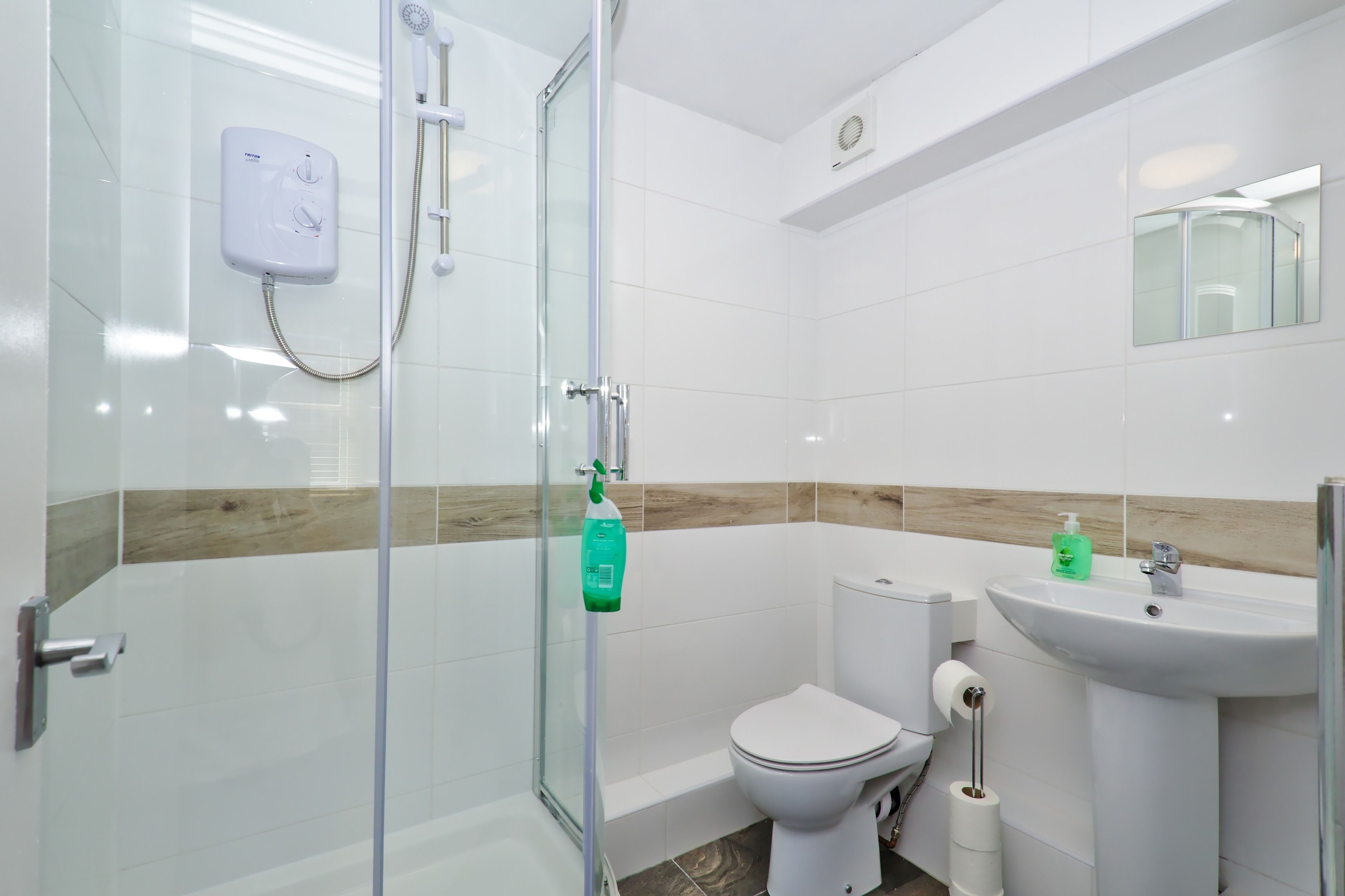 A modern bathroom with a glass-enclosed shower, a toilet, and a sink.