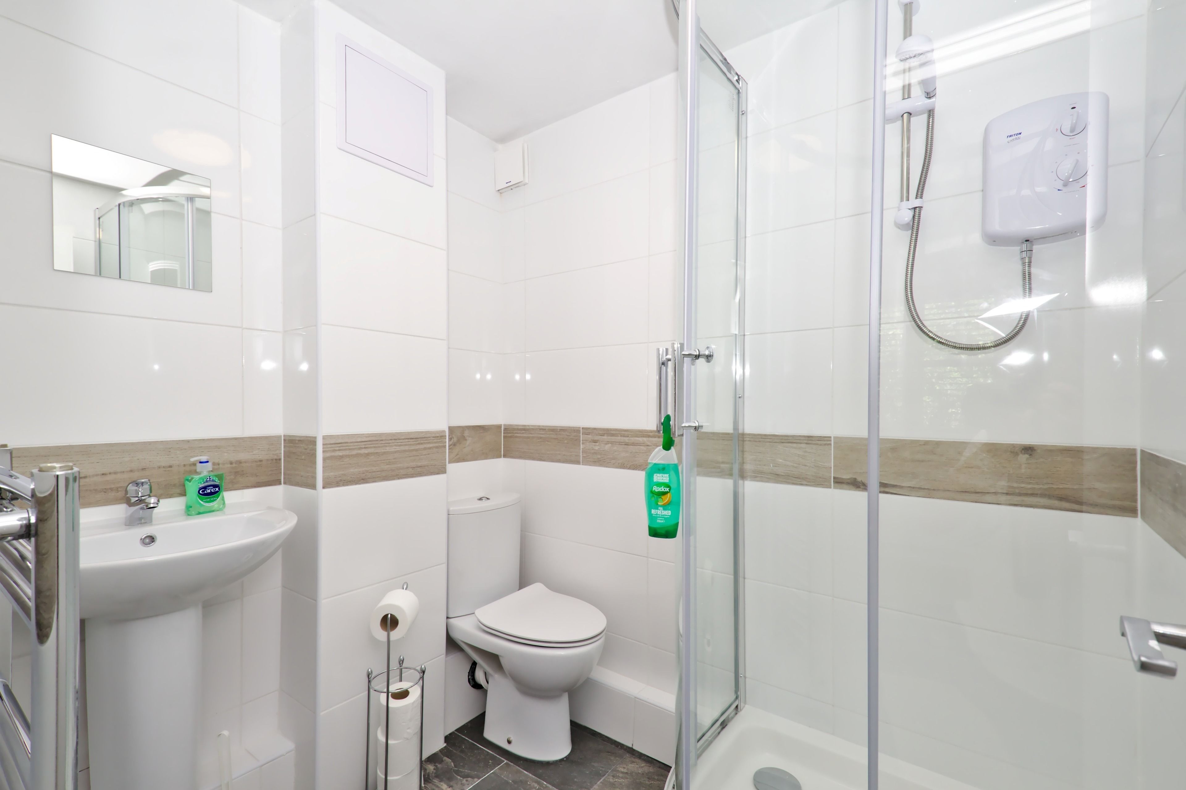 A modern bathroom with a glass-enclosed shower, a white sink with a mirror, and a toilet.