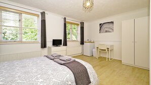 A bedroom with a bed, a desk, a chair, a television, and a wardrobe. - Harlinger Lodge Annexe (London)