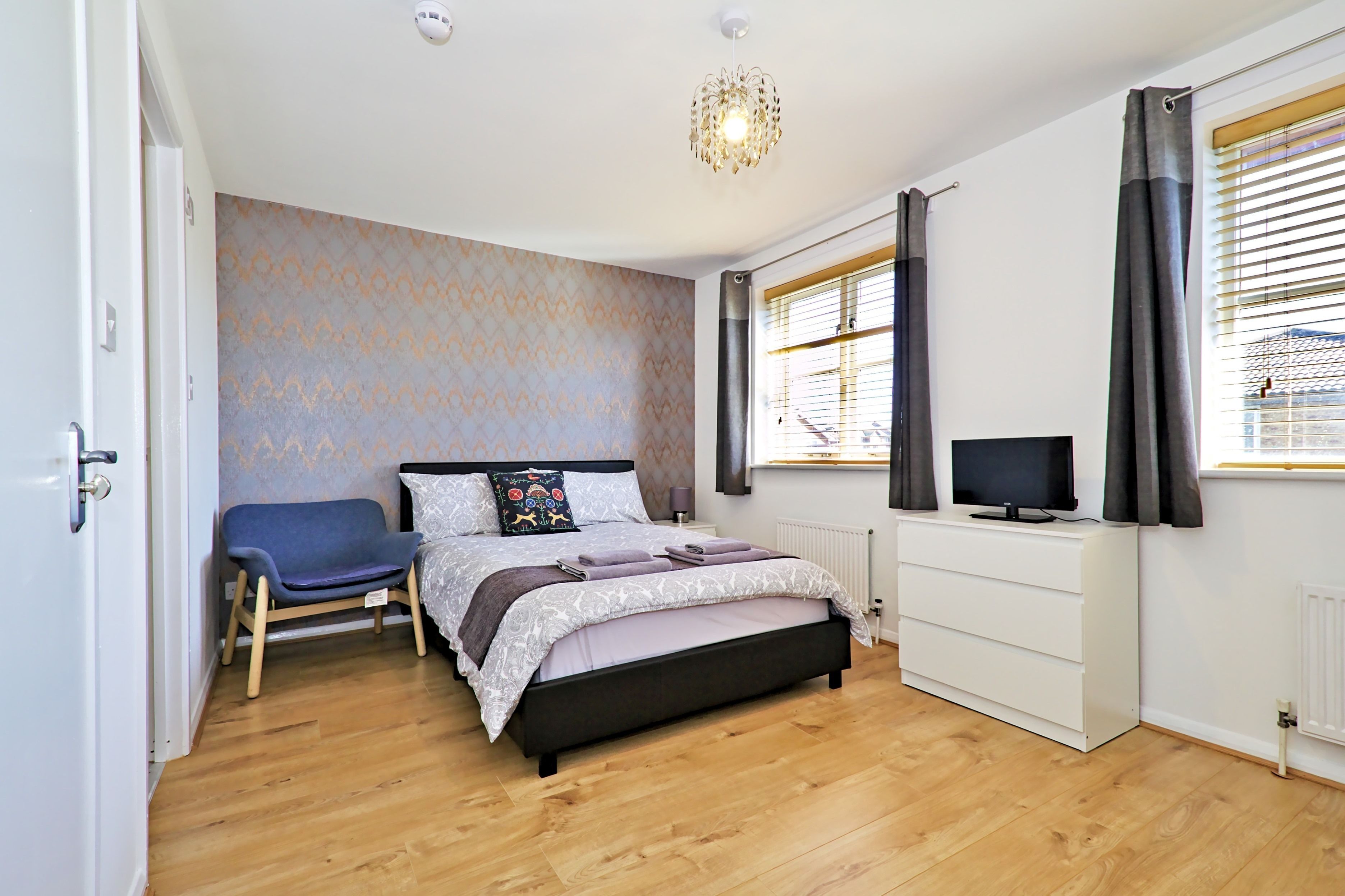 Une chambre à coucher avec un lit, une chaise, un téléviseur et un radiateur.
