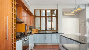 Eine moderne Küche mit Holzausstattung, einem eingebauten Backofen und einem großen Fenster mit Jalousien.