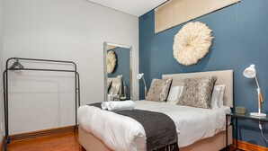 Ein Schlafzimmer mit Bett, Nachttischen, einem Spiegel und einem Wanddekor.