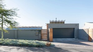 A modern building with a gated entrance, a garage, and solar panels on the roof. - Nature Lover's Nest at the Foot of Table Mountain (Cape Town)