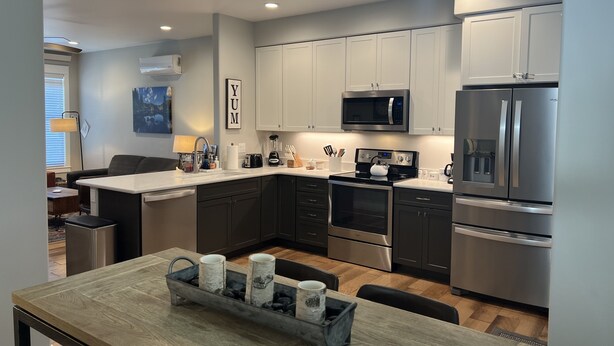 A modern kitchen with stainless steel appliances, a central island with mugs, and a 'YUM' sign on the wall. - Beautiful New Luxury Condo in Downtown Salida! #0676 (Salida)