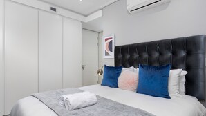Un dormitorio moderno con una cama grande, un cabecero y una puerta.