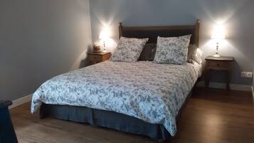 A bedroom with a wooden bed, floral bedding, two bedside tables with lamps, and a nightstand.
