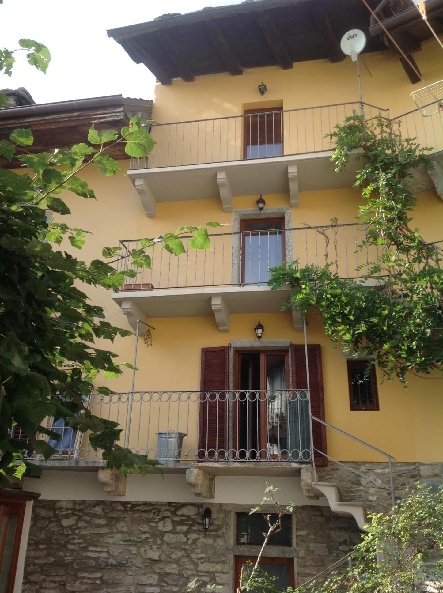 A multi-story building with balconies, stone walls, and a yellow facade.