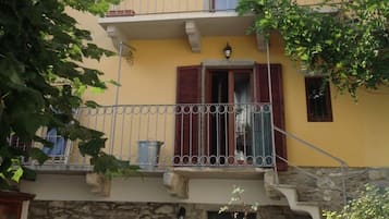 A multi-story building with balconies, stone walls, and a yellow facade.