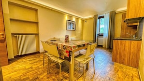 A compact dining area with a table and chairs, a radiator, a framed picture on the wall, and a window with curtains. - TABOR - APARTMENT sleeps 6 - 2nd floor (Bardonecchia)