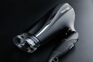 Un secador de pelo negro con boquilla transparente y diseño elegante, etiquetado como "TESCOM".