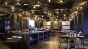 A restaurant interior with a long counter, multiple tables, and chairs. - Hotel Termas Chillán (Pinto)