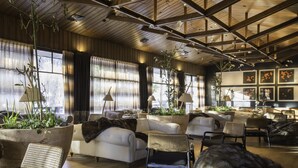A spacious living area with multiple seating options, large windows, and indoor plants. - Hotel Termas Chillán (Pinto)