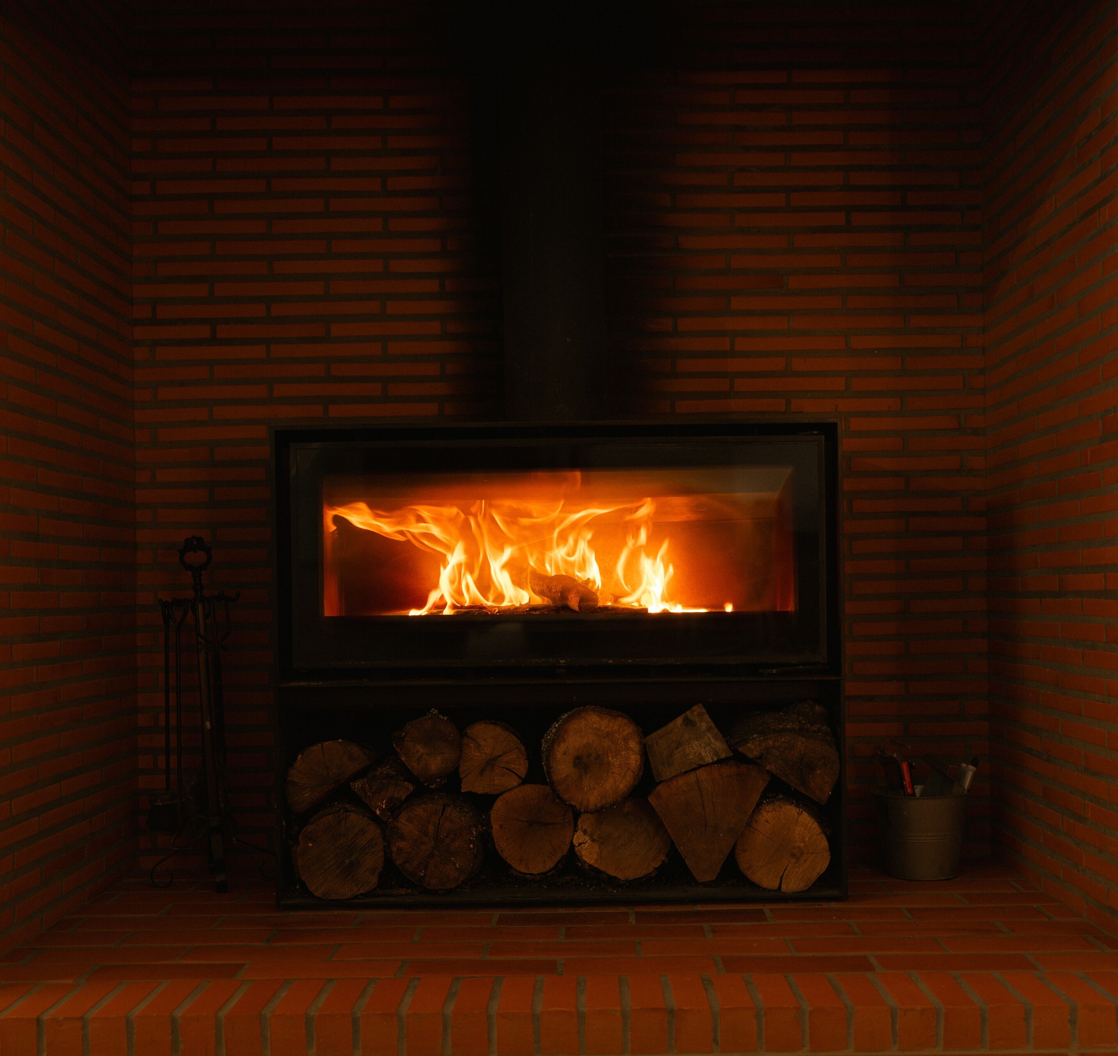 Una chimenea con fuego a la vista, rodeada por un muro de ladrillo.