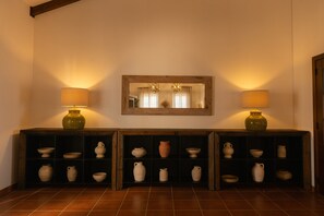 A hallway with a wooden floor, a mirror on the wall, and two lamps on either side.