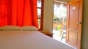 A room with a bed, a wooden door, and a view of a garden. - Hostal Tierra y Mar (Manglaralto)