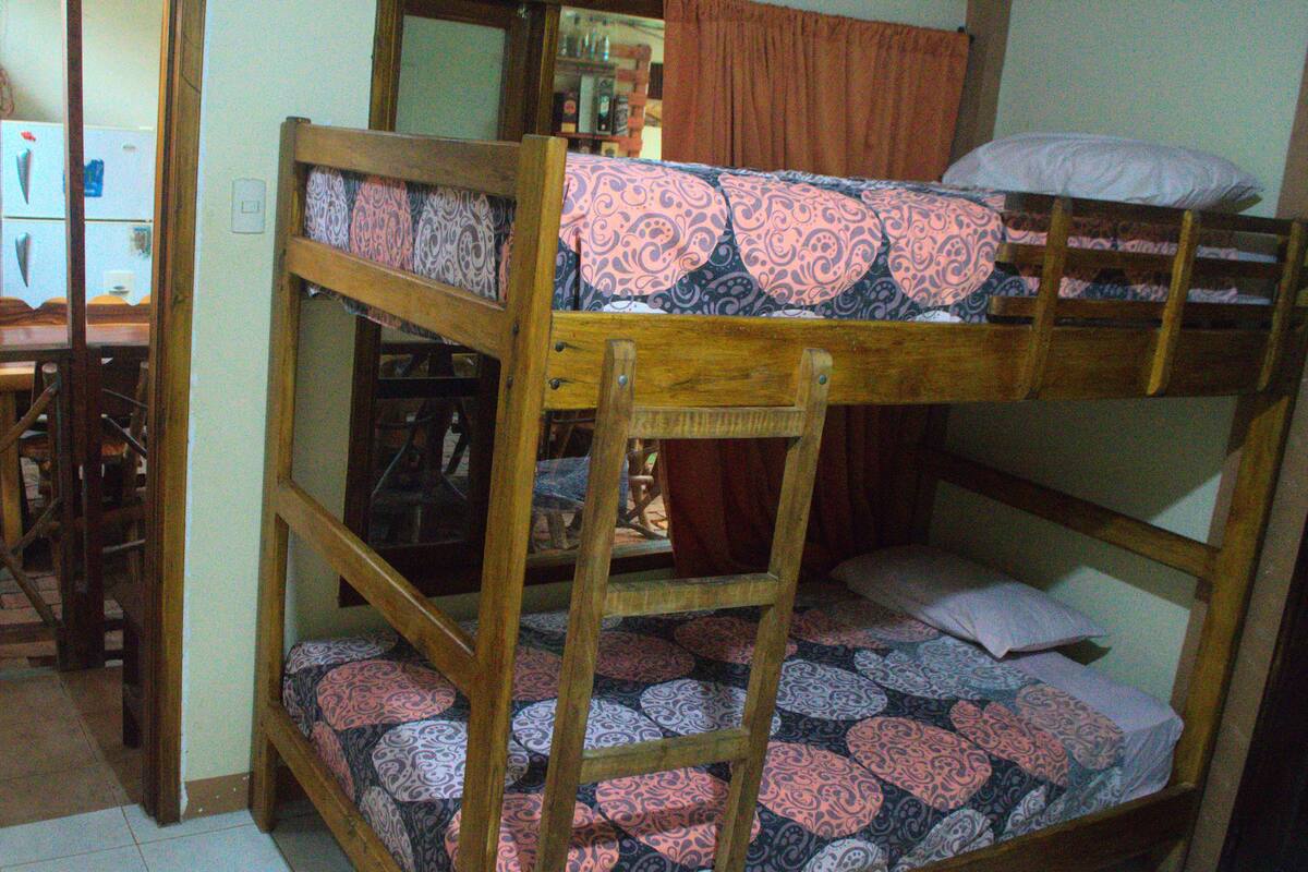 A bunk bed with patterned bedding, a wooden headboard, and a mirror above the bed.