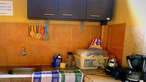 A kitchen with a sink, cabinets, and various kitchen items like a coffee maker and a basket. - Hostal Tierra y Mar (Manglaralto)