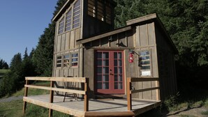 A wooden cabin with a red door, a small porch, and a fire extinguisher mounted on the wall. - Clydesdale Outpost (Amboy)