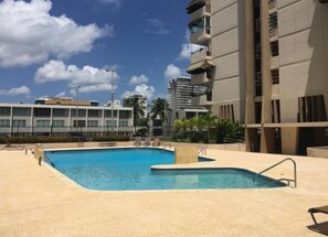 Relax by the pool with lounge chairs and a deck area, surrounded by palm trees and greenery.