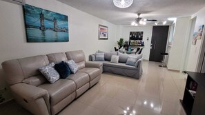 Relax in this stylish living room with a comfortable sofa and dining area, featuring a bar with a selection of drinks.