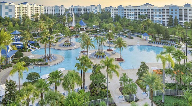 Un complexe hôtelier doté de plusieurs piscines, de palmiers et d’un grand ensemble de bâtiments en arrière-plan.