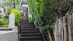 A staircase leading up to a building, surrounded by greenery and a bamboo fence. - Kolpin's Cabana cozy condo with 2 balconies to enjoy the tropical weather.  (Playa Del Coco)