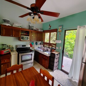 A kitchen with wooden cabinets, a stove, a microwave, and a ceiling fan.