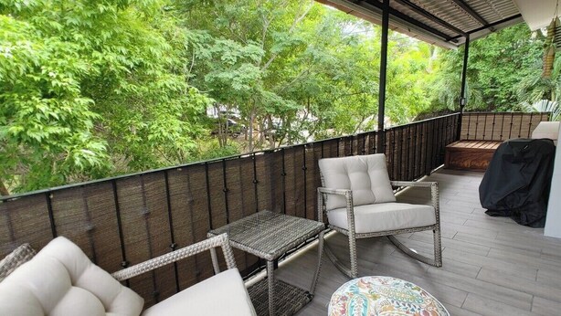 A covered outdoor seating area with wicker furniture and a patterned ottoman. - Kolpin's Cabana cozy condo with 2 balconies to enjoy the tropical weather.  (Playa Del Coco)