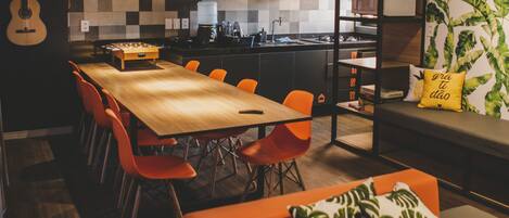 Una cocina moderna con una isla grande, un comedor con sillas color naranja y una zona de estar acogedora con sofá y cojines.
