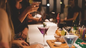 A bar setting with a martini glass, a cocktail, and a small dish of food on a wooden board. - Wanderlust Hostel (Maceió)