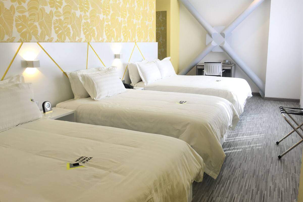 A hotel room with two beds, a desk, and a chair.