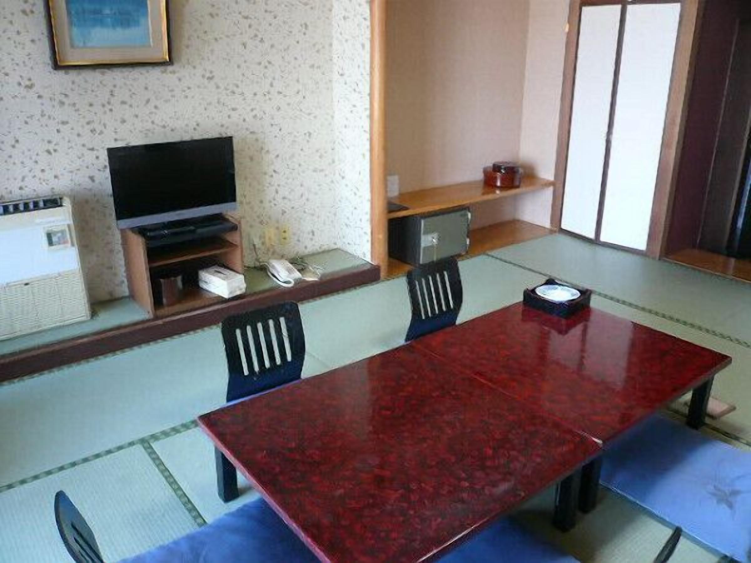A traditional Japanese-style room with tatami flooring, a low table, and a television.