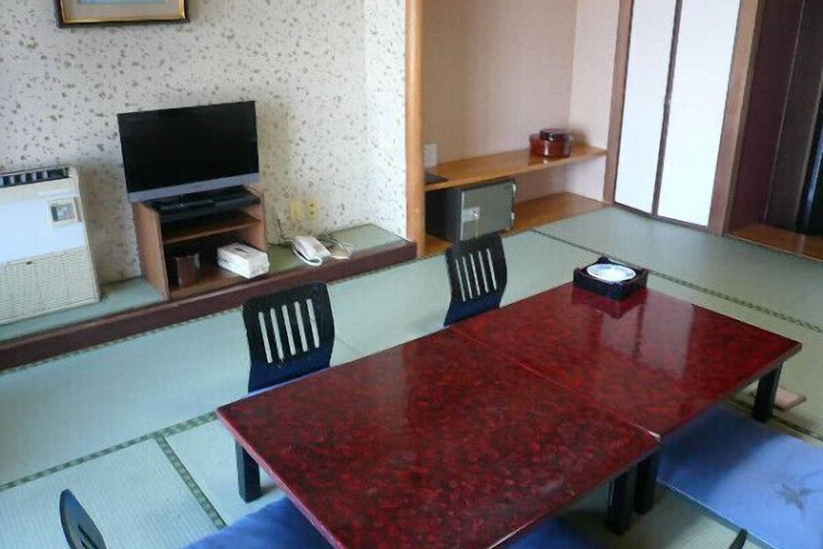 A traditional Japanese-style room with tatami flooring, a low table, and a television.