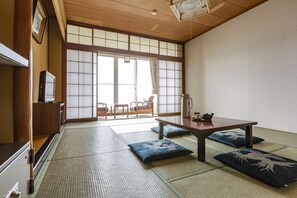 Una habitación japonesa tradicional con suelo de tatami, una mesa de madera baja, cojines y puertas correderas shoji.