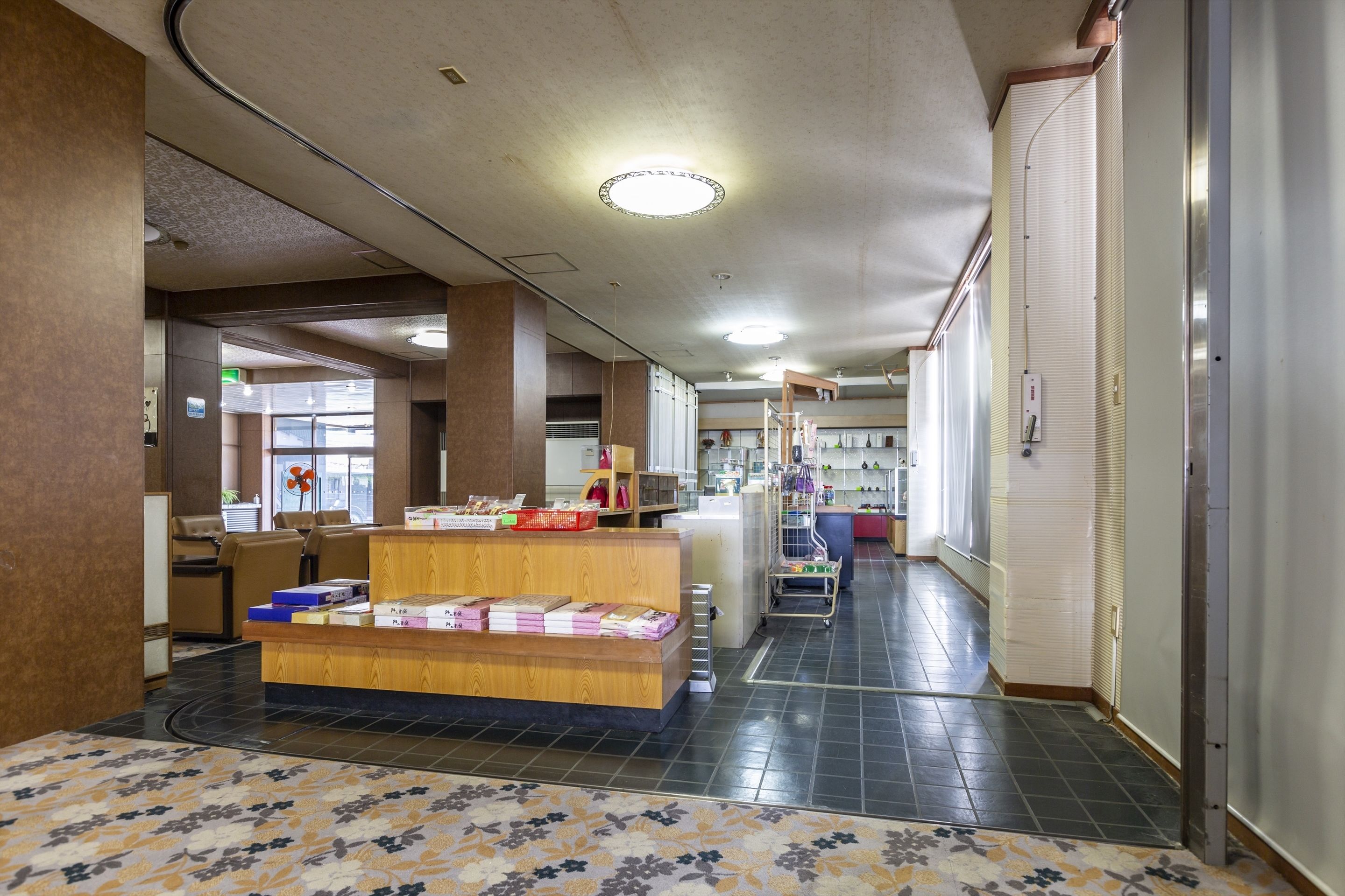 A hotel lobby with a reception desk, seating area, and a staircase leading to upper floors.