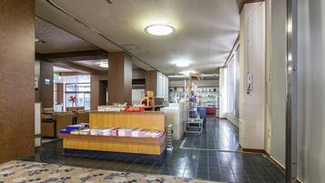 A hotel lobby with a reception desk, seating area, and a staircase leading to upper floors.