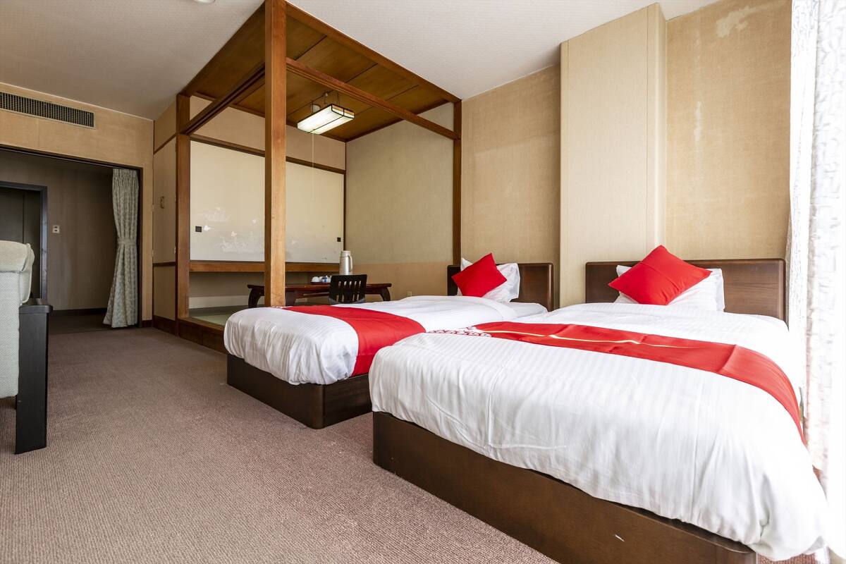 A hotel room with two beds, a wooden ceiling, a large mirror, and a wardrobe.