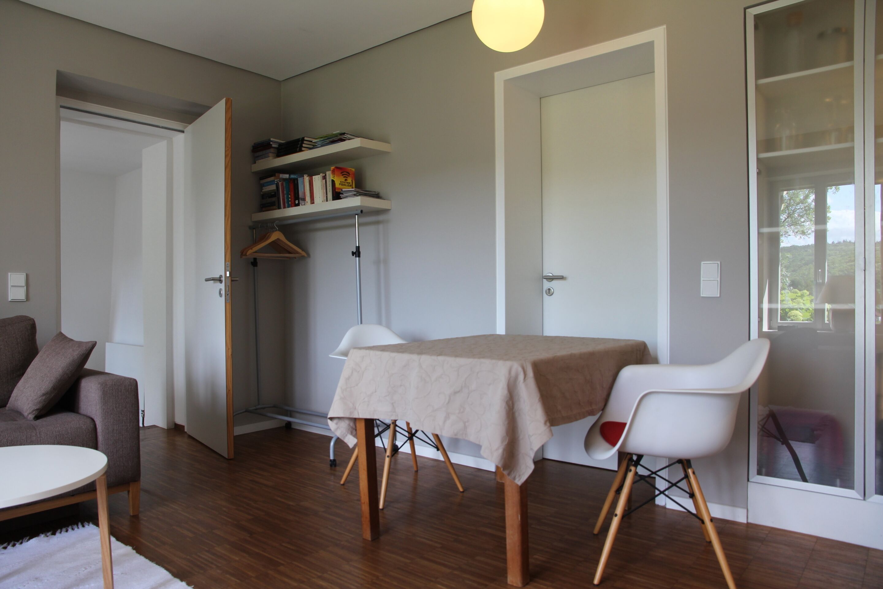 A modern living room with a dining table, a sofa, and a bookshelf.