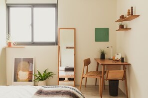 A bedroom with a bed, a desk, chairs, a mirror, shelves, and a window. - Boy Apartment (Hualien City)