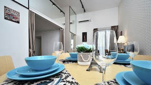 A dining area with a table set for four, featuring blue plates and clear glassware. - Cozy Family Suite Apartment (Kuala Lumpur)