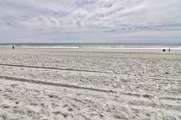 A sandy beach with footprints and a person walking.