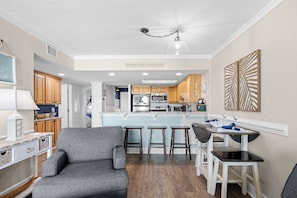 A modern kitchen with a central island, wooden cabinets, and a dining area with stools.