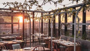 An outdoor dining area with tables and chairs, a view of the cityscape, and a sunset in the background. - Novotel Paris Porte De Versailles (Paris)
