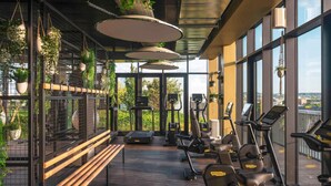 A gym with exercise equipment, a bench, and hanging plants. - Novotel Paris Porte De Versailles (Paris)