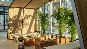 A modern room with a large window, a bed, wooden furniture, and potted plants. - Novotel Paris Porte De Versailles (Paris)