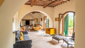 A spacious living area with a high ceiling, a sofa set, a yellow armchair, and a dining table. - Delightful secluded Tuscan farmhouse with pool, near the hilltop town of Cetona. (Cetona, SI)