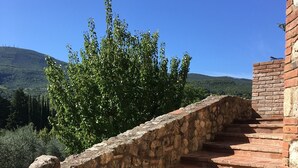 A stone staircase leading up to a building with a view of a hillside and trees. - Delightful secluded Tuscan farmhouse with pool, near the hilltop town of Cetona. (Cetona, SI)