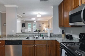 A kitchen with granite countertops, stainless steel appliances, wooden cabinets, and a black stove.